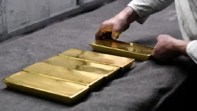 Gold bars with a decreasing trend chart representing the decline in gold prices due to the US Federal Reserve's hawkish stance