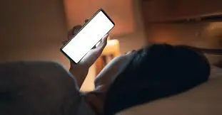 Person using a mobile phone in bed at night.