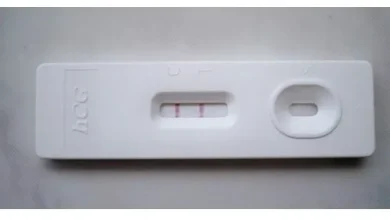 A woman holding a pregnancy test kit and looking at the results.