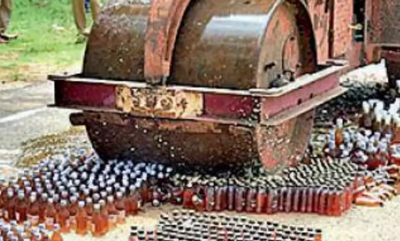 A large pile of confiscated liquor bottles being destroyed by Rajkot city police.