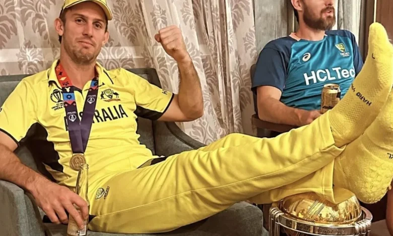 Mitchell Marsh holding the World Cup trophy with a regretful expression on his face
