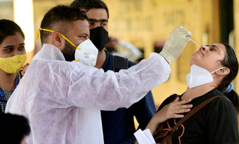 A doctor in PPE attire examines a patient, symbolizing the ongoing fight against COVID-19 in India and its potential impact on Singapore.