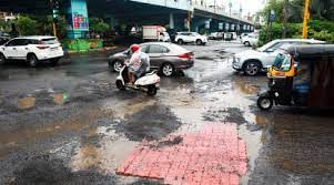 A frustrated motorist gestures at a large pothole in a busy Mumbai street, highlighting the negligence of government institutions in addressing the city's pothole problem despite court orders.