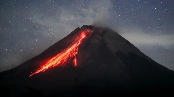 A photorealistic depiction of Mount Merapi erupting, spewing ash and lava into the sky. The surrounding landscape is shrouded in smoke and haze, and the sun is obscured by the volcanic cloud.