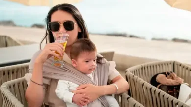 Woman breastfeeding while drinking beer on the beach