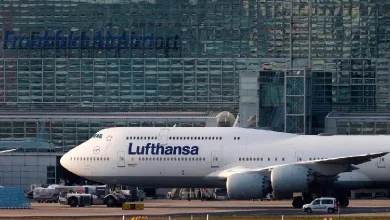 Lufthansa airplane on a tarmac with emergency vehicles in the background.