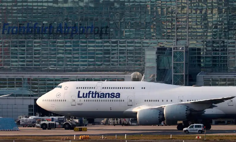 Lufthansa airplane on a tarmac with emergency vehicles in the background.