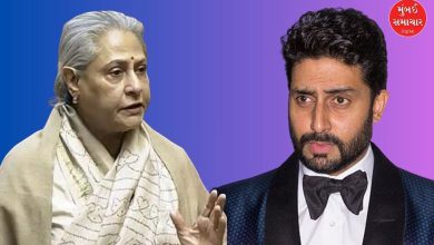 અભિષેક બચ્ચન હસતા ચહેરા સાથે ઇન્ટરવ્યુ આપી રહ્યા છે, તેમની પાછળ જયા બચ્ચનનો ફોટો.