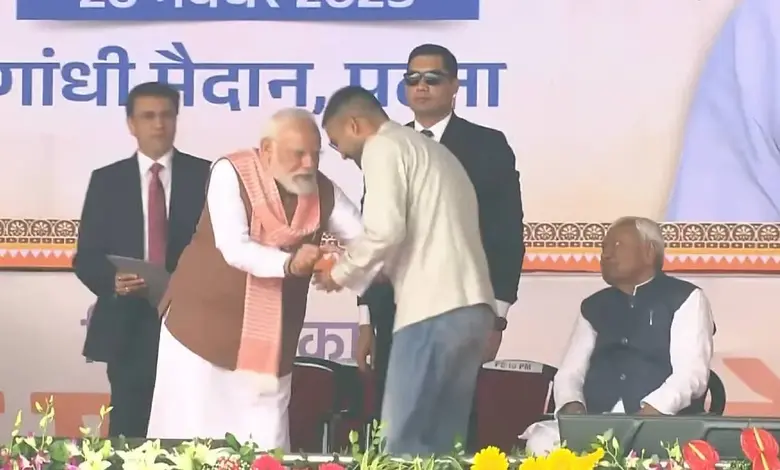 બિહારના મંત્રી દીપક પ્રકાશ શપથગ્રહણ સમારોહમાં ડેનિમ જીન્સ, શર્ટ અને ક્રોક્સ પહેરીને શપથ લઈ રહ્યા છે; બાજુમાં નીતીશ કુમાર અને અન્ય નેતાઓ.