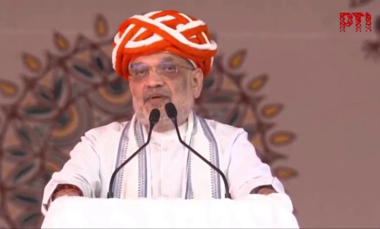 બનાસ ડેરીના સણાદર પ્લાન્ટ ખાતે કેન્દ્રીય ગૃહ અને સહકાર પ્રધાન અમિત શાહ વિવિધ પ્રકલ્પોના લોકાર્પણ અને મુલાકાત દરમિયાન, પાછળ બનાસ ડેરીનો લોગો અને ભીડ દેખાય છે.