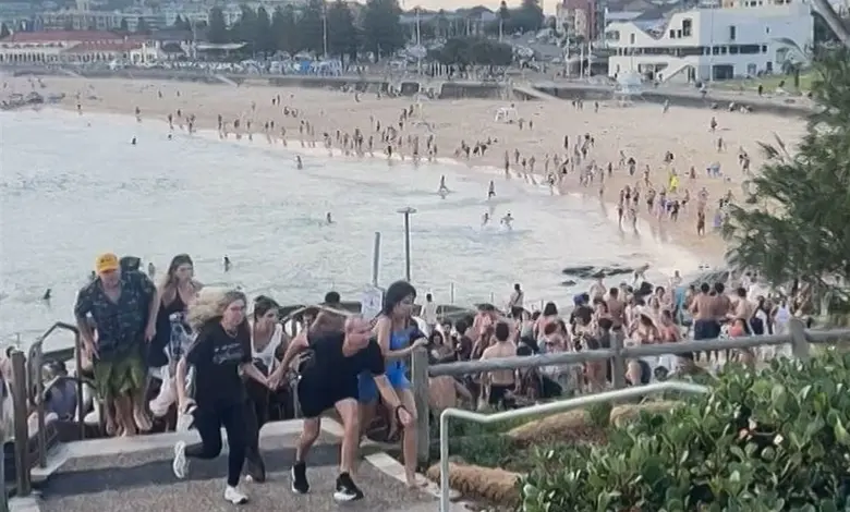 ઓસ્ટ્રેલિયાના સિડનીમાં બોન્ડી બીચ પર થયેલા આતંકી હુમલાનું દૃશ્ય, પોલીસ અને સુરક્ષાકર્મીઓ ઘટનાસ્થળે, પીડિતોને મદદ કરતા.