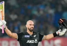 રાજકોટમાં ભારત સામે સદી ફટકાર્યા બાદ બેટ ઊંચું કરીને ઉજવણી કરતો ડેરિલ મિચલ.