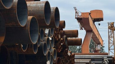 Large industrial seamless steel pipes stacked in an Indian manufacturing plant.