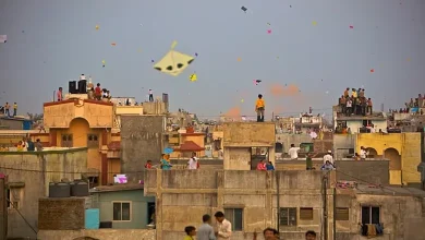 અમદાવાદની પોળમાં ધાબા પર પતંગ ચગાવતા લોકો અને આકાશમાં ઉડતા રંગબેરંગી પતંગો.