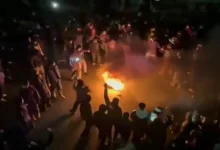 Protesters gathered in Tehran streets with smoke and dramatic atmosphere representing the unrest in Iran.