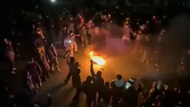 Protesters gathered in Tehran streets with smoke and dramatic atmosphere representing the unrest in Iran.