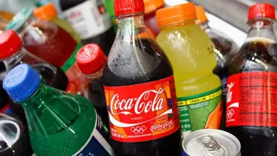 ખાંડયુક્ત ઠંડા પીણાં, ફળોના રસ અને આલ્કોહોલની બોટલો સાથે સ્વાસ્થ્ય જાગૃતિનું પ્રતીકાત્મક ચિત્ર.